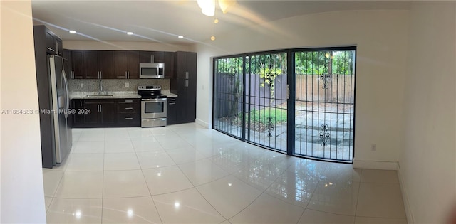 kitchen with dark brown cabinets, stainless steel appliances, sink, light tile patterned floors, and tasteful backsplash