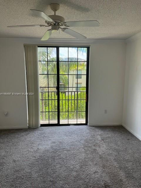 carpeted spare room with ceiling fan and a textured ceiling