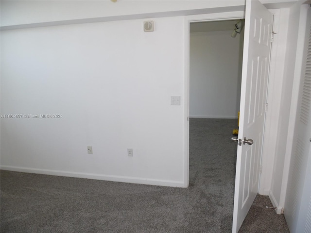 unfurnished room featuring dark colored carpet