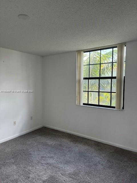 carpeted empty room featuring a textured ceiling