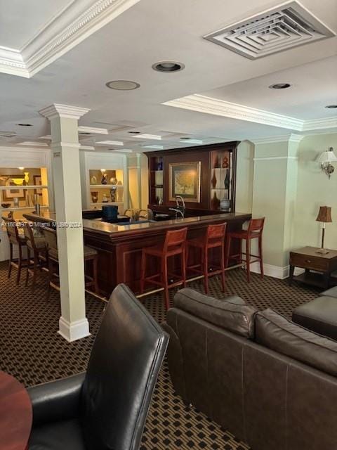 interior space with decorative columns, bar area, carpet flooring, and crown molding