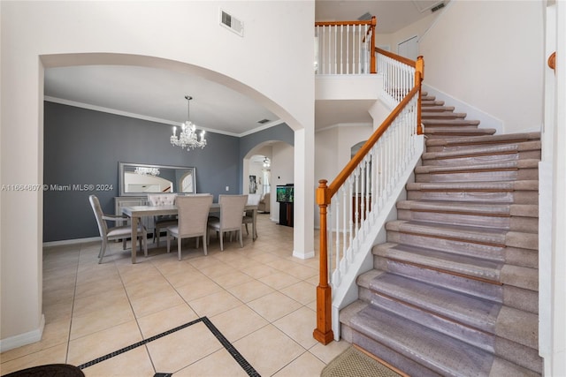 staircase with a high ceiling, ornamental molding, an inviting chandelier, and tile patterned floors