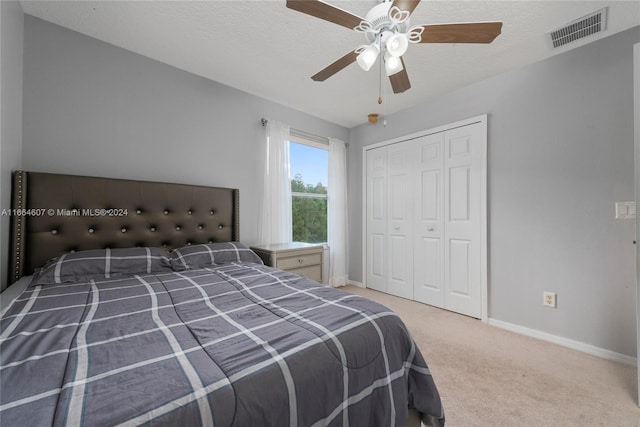 carpeted bedroom featuring a closet, ceiling fan, and a textured ceiling