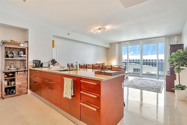 kitchen with a wall of windows, sink, light tile patterned floors, and light stone counters