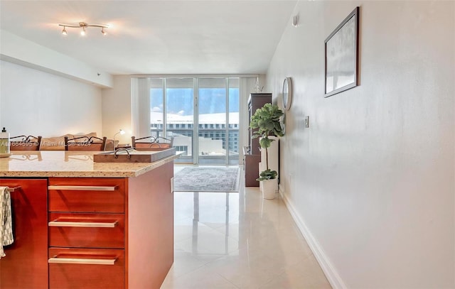 kitchen with light stone counters, a wall of windows, and light tile patterned floors