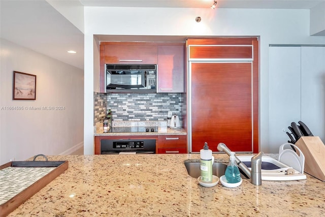 kitchen with light stone countertops, sink, tasteful backsplash, and black appliances