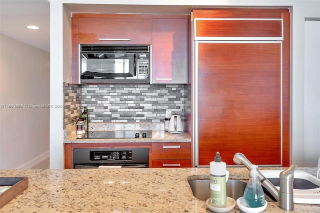 kitchen with black appliances, sink, light stone counters, and tasteful backsplash