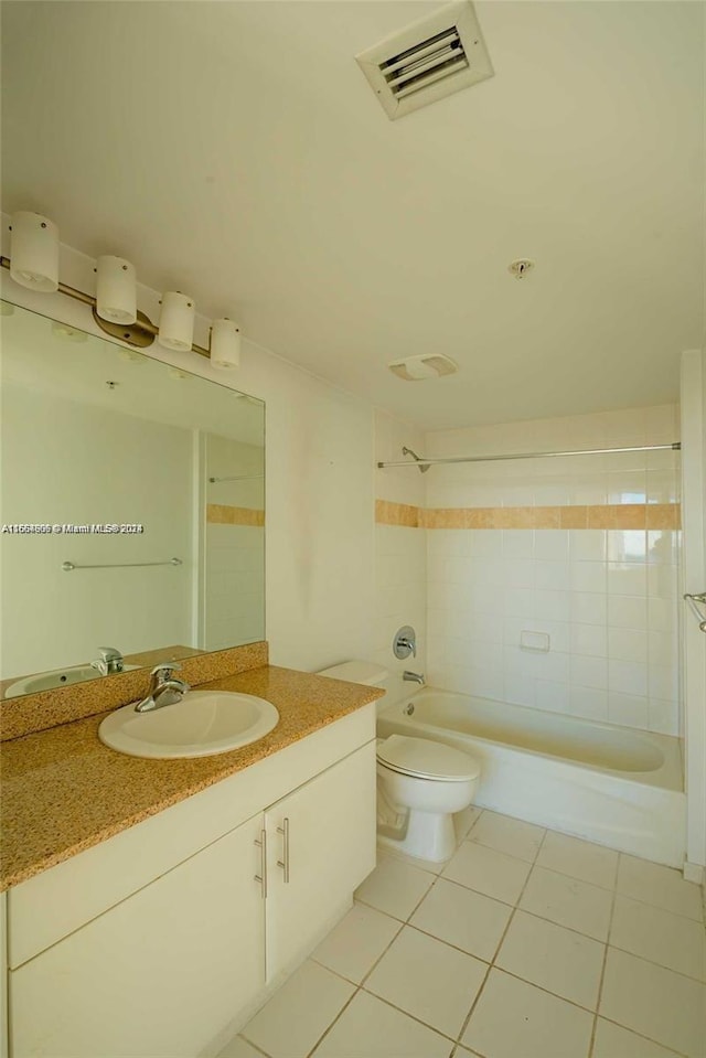 full bathroom with tile patterned floors, tiled shower / bath, vanity, and toilet