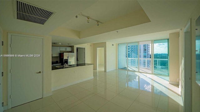 1861 NW S River Dr Unit 1404, Miami, FL 33125 - spare room featuring track lighting, a raised ceiling, light tile patterned floors, and baseboards