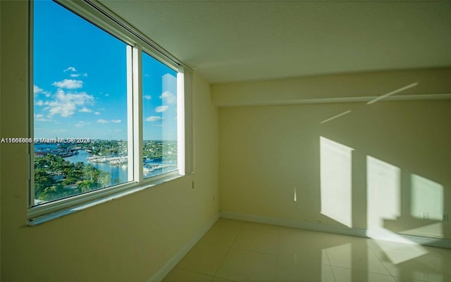 empty room with a water view and light tile patterned flooring