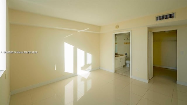 1861 NW S River Dr Unit 1404, Miami, FL 33125 - unfurnished bedroom featuring light tile patterned floors, baseboards, a spacious closet, a closet, and connected bathroom