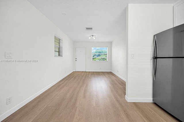 empty room with light hardwood / wood-style flooring and a textured ceiling