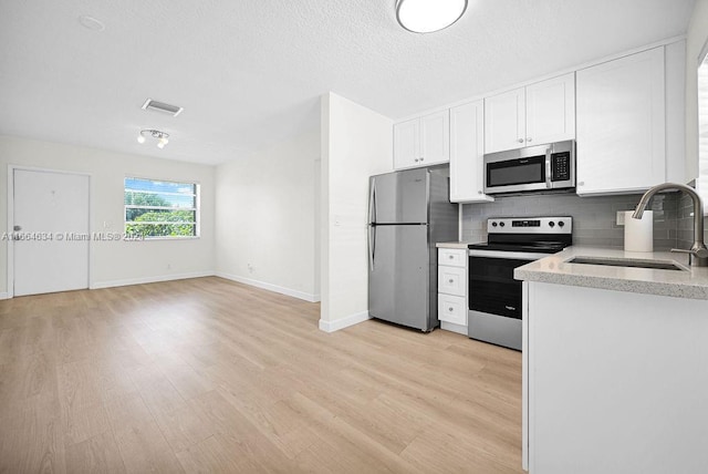 kitchen featuring decorative backsplash, light hardwood / wood-style floors, white cabinetry, and stainless steel appliances