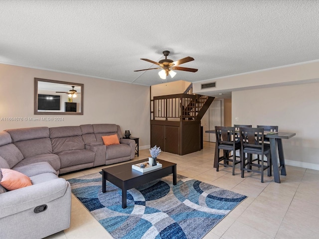 tiled living room with ceiling fan, a textured ceiling, and crown molding