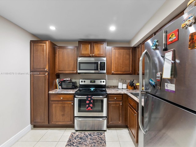 kitchen featuring light stone countertops, stainless steel appliances, and light tile patterned floors