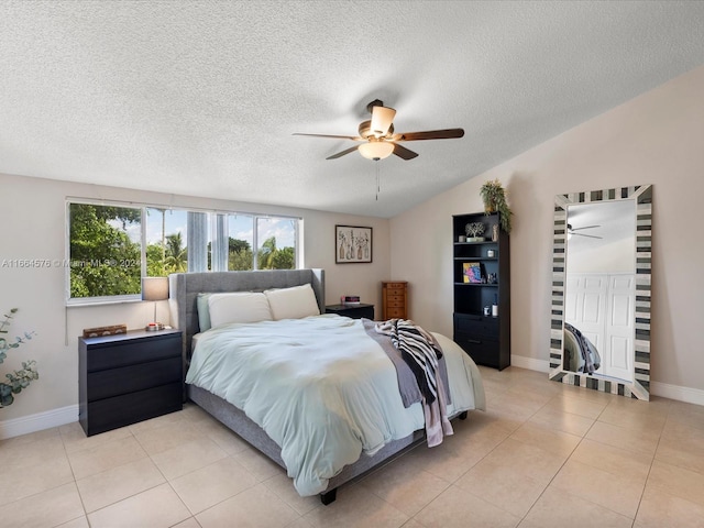 tiled bedroom featuring ceiling fan, a textured ceiling, and lofted ceiling