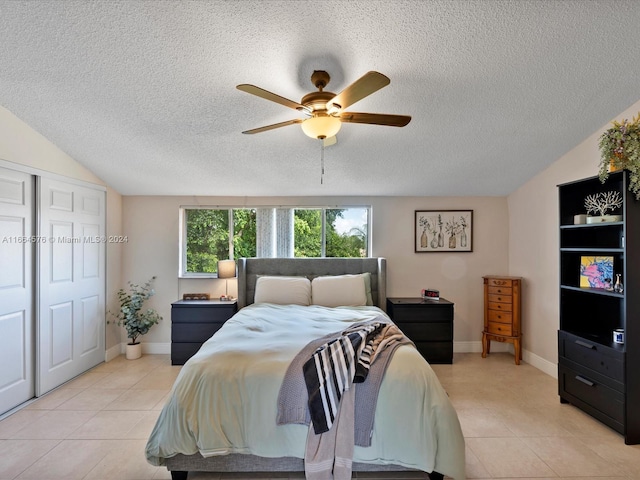 bedroom with ceiling fan, lofted ceiling, light tile patterned floors, a textured ceiling, and a closet