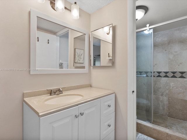 bathroom with a textured ceiling, walk in shower, and vanity