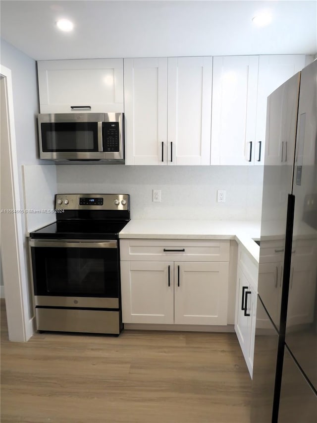 kitchen featuring appliances with stainless steel finishes, light hardwood / wood-style floors, and white cabinetry