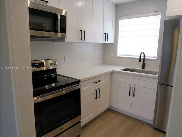 kitchen featuring light hardwood / wood-style flooring, white cabinets, appliances with stainless steel finishes, and sink