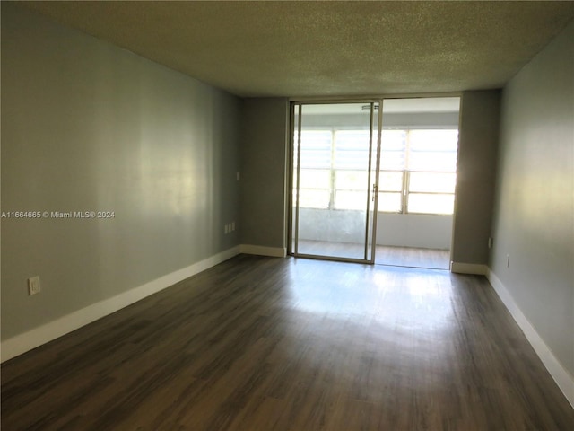 unfurnished room with a textured ceiling and dark wood-type flooring