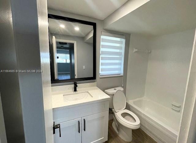 full bathroom with washtub / shower combination, hardwood / wood-style floors, vanity, and toilet