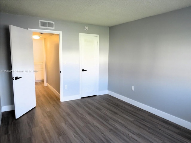 unfurnished bedroom featuring a closet, a textured ceiling, and dark wood-type flooring