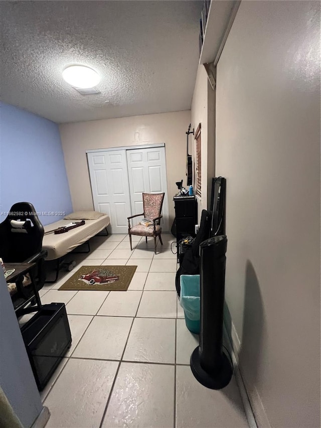 interior space featuring a textured ceiling, tile patterned floors, and a closet