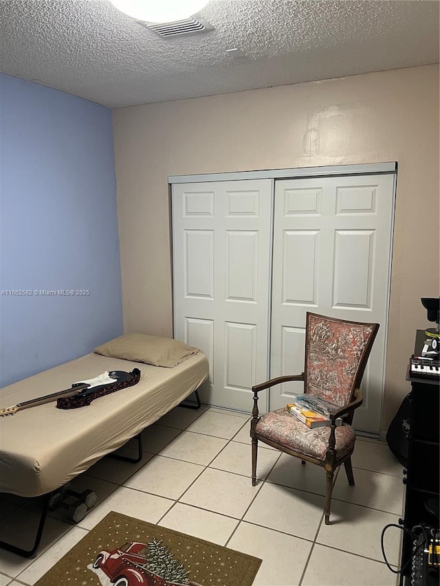 tiled bedroom with a textured ceiling and a closet