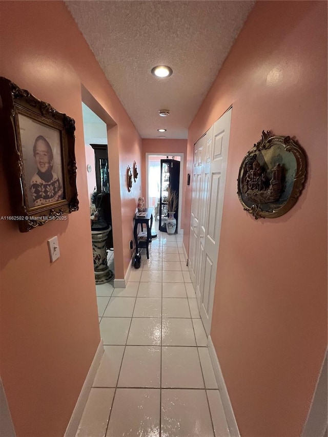 hall with light tile patterned floors and a textured ceiling