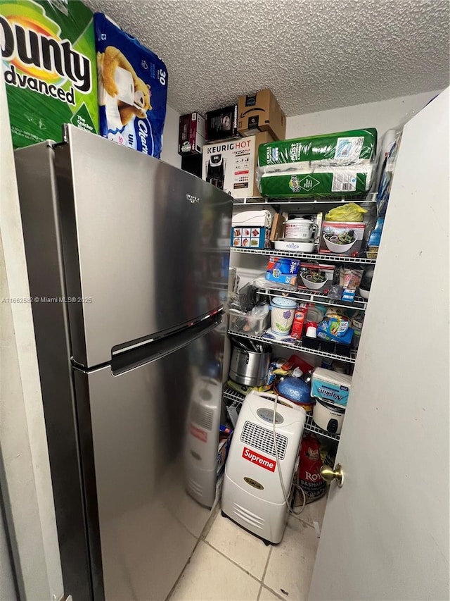 kitchen featuring stainless steel fridge, a textured ceiling, and light tile patterned flooring