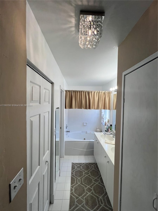 bathroom with tile patterned flooring, vanity, a notable chandelier, and tiled tub