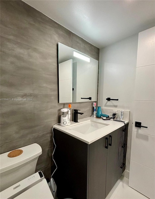 bathroom featuring tile walls, vanity, toilet, and tile patterned floors