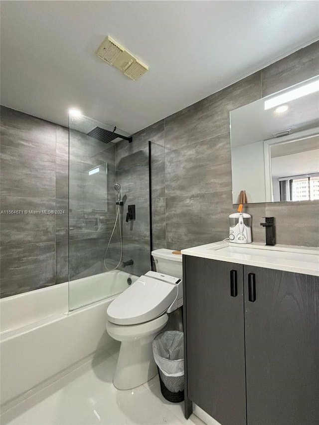 full bathroom featuring tile walls, combined bath / shower with glass door, vanity, and toilet