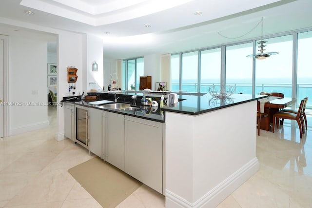 kitchen featuring white cabinets, a water view, sink, an island with sink, and decorative light fixtures