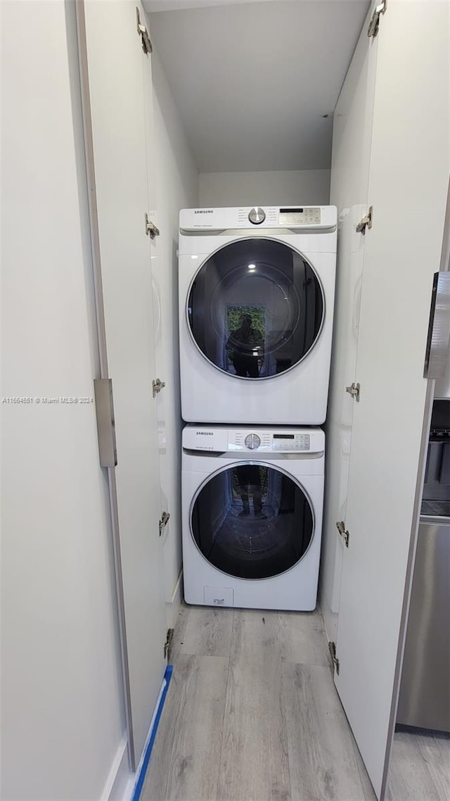 laundry area featuring stacked washer / drying machine and light hardwood / wood-style floors