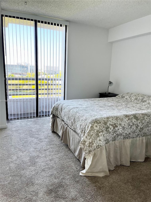 bedroom with a textured ceiling, carpet floors, and access to exterior