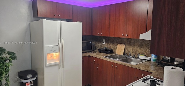 kitchen with decorative backsplash, white fridge with ice dispenser, and sink