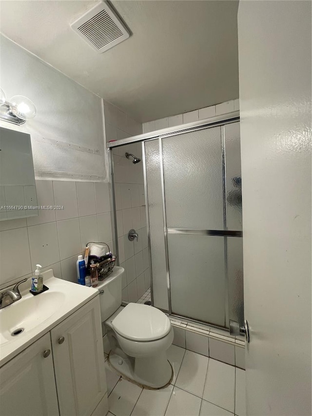 bathroom featuring tile walls, a shower with shower door, vanity, tile patterned flooring, and toilet