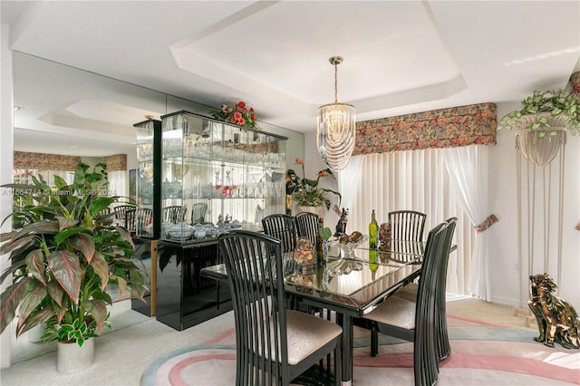 carpeted dining room featuring a raised ceiling and an inviting chandelier