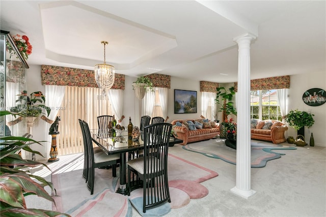 dining room featuring a tray ceiling, decorative columns, light colored carpet, and a chandelier