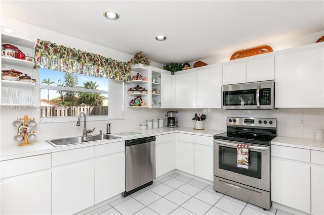 kitchen with light tile patterned flooring, sink, white cabinets, backsplash, and appliances with stainless steel finishes