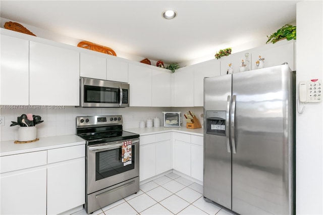 kitchen with stainless steel appliances, white cabinets, light tile patterned floors, and tasteful backsplash