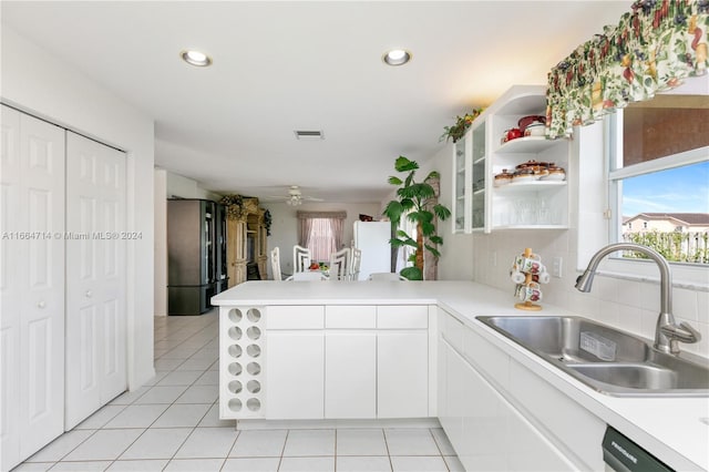 kitchen featuring sink, white cabinets, kitchen peninsula, stainless steel refrigerator, and light tile patterned floors