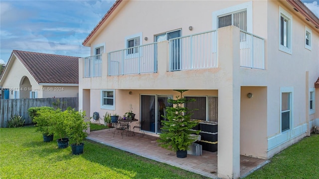 rear view of house featuring a balcony, a lawn, and a patio