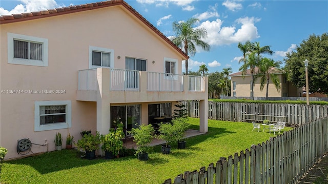 rear view of house with a balcony and a lawn