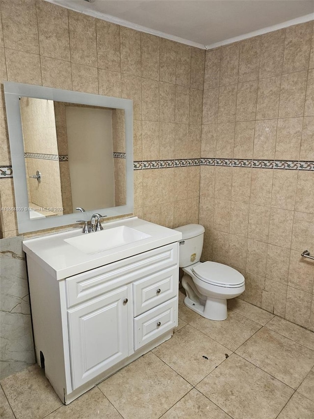 bathroom featuring vanity, toilet, tile walls, crown molding, and tile patterned flooring