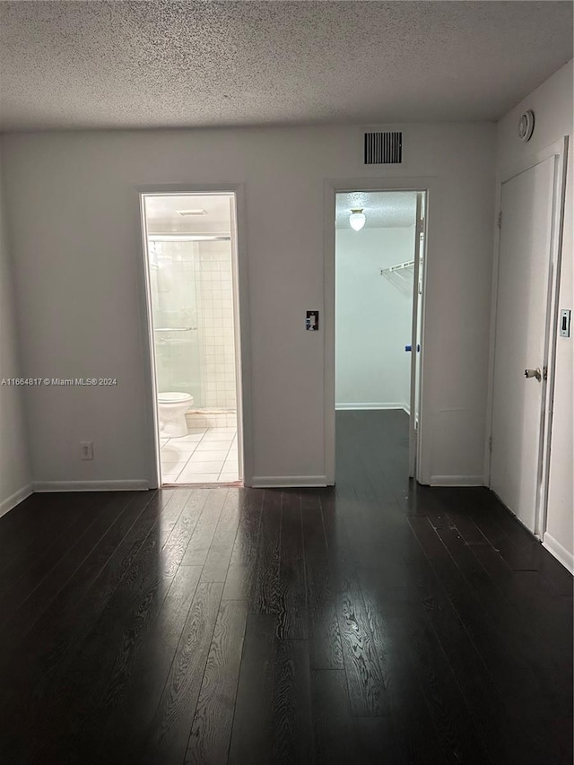 empty room featuring a textured ceiling and dark wood-type flooring