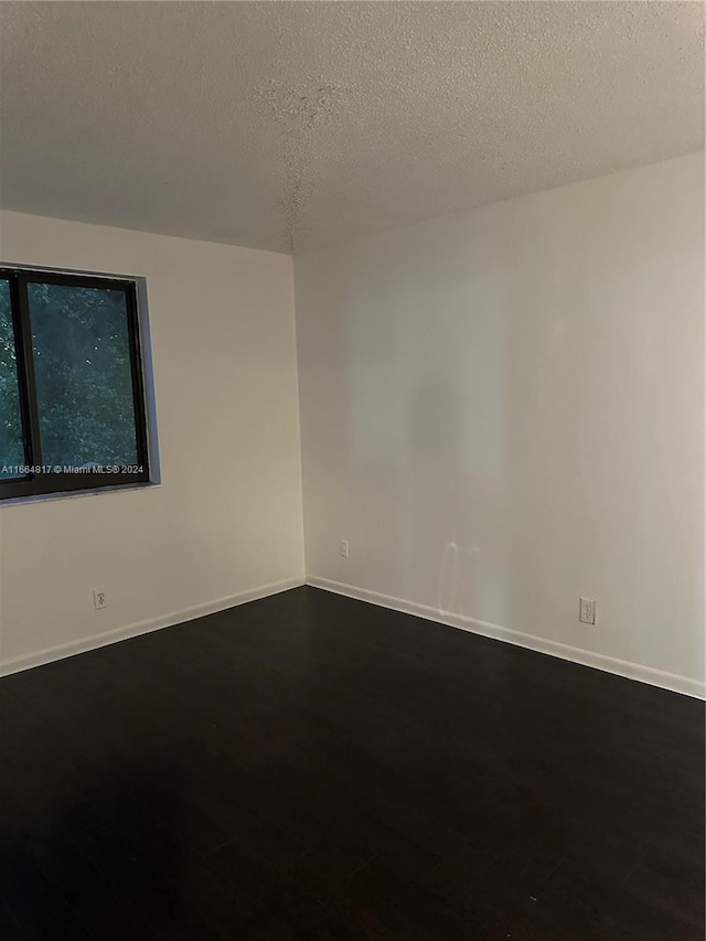 unfurnished room with hardwood / wood-style floors and a textured ceiling