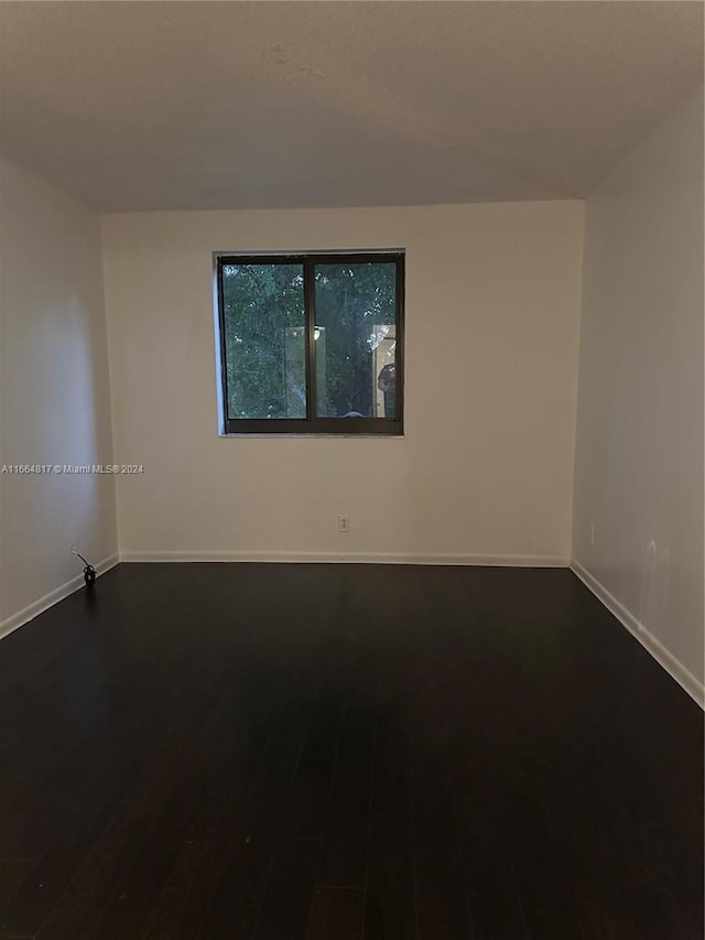 unfurnished room with dark hardwood / wood-style flooring